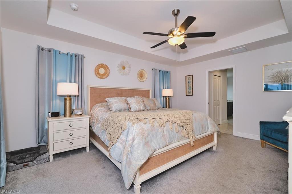 PRIMARY BEDROOM featuring a tray ceiling with a ceiling fan