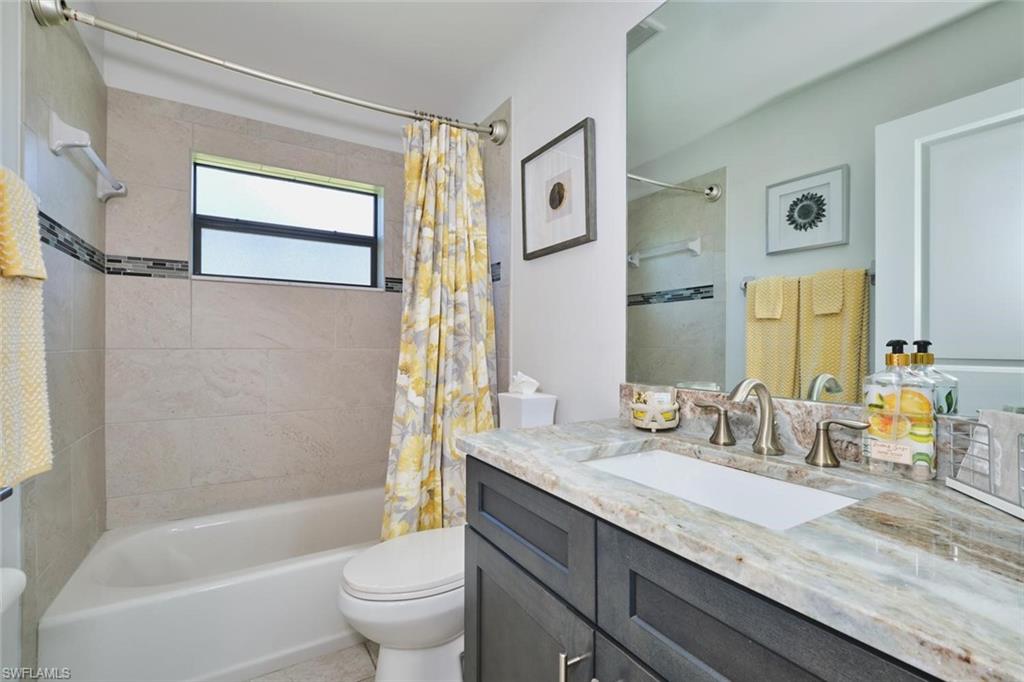 Bathroom featuring a built-in tub with tile surround, decorative accent tile band, and a window