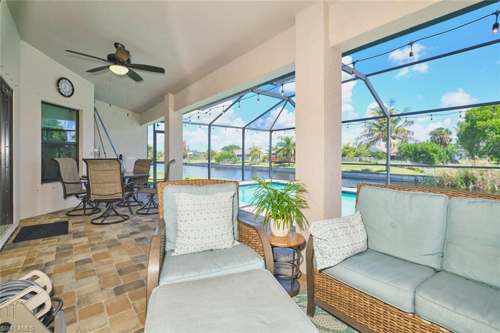 Screened lanai featuring a ceiling fan with light, string lighting, and a view of the water and pool