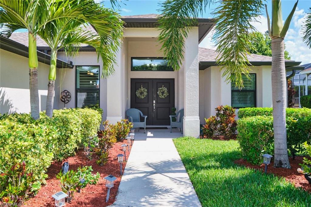 Stucco exterior with a covered entry, dark double doors, and a transom window