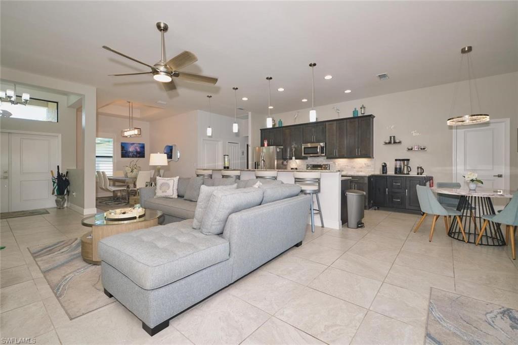 Open-concept living area featuring light-toned tile flooring, recessed lighting, and a ceiling fan
