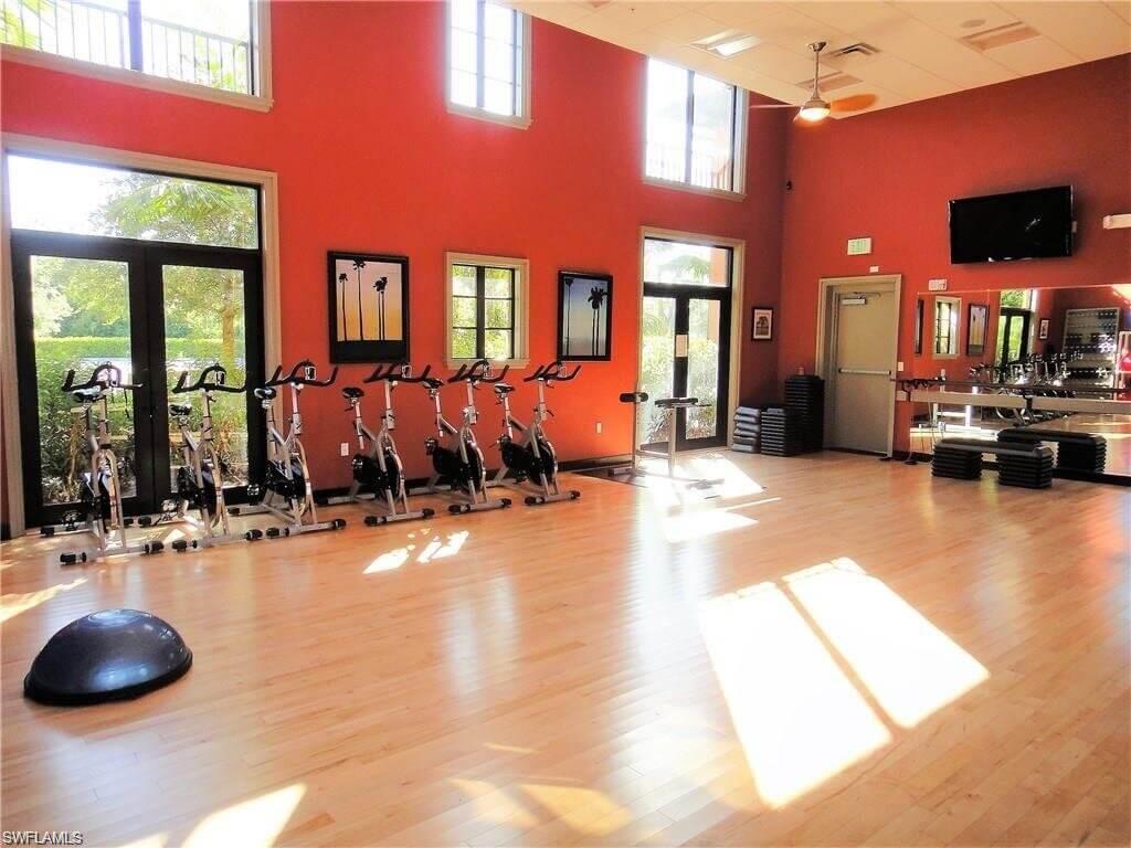 Group fitness room featuring light wood-finish flooring, high ceilings, and floor-to-ceiling windows