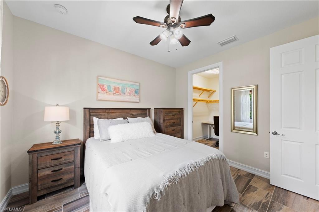 Secondary bedroom featuring wood-finish tile flooring, a ceiling fan with integrated lighting, WALK-IN CLOSET and neutral wall tones. NEW TILE FLOOR (2018)