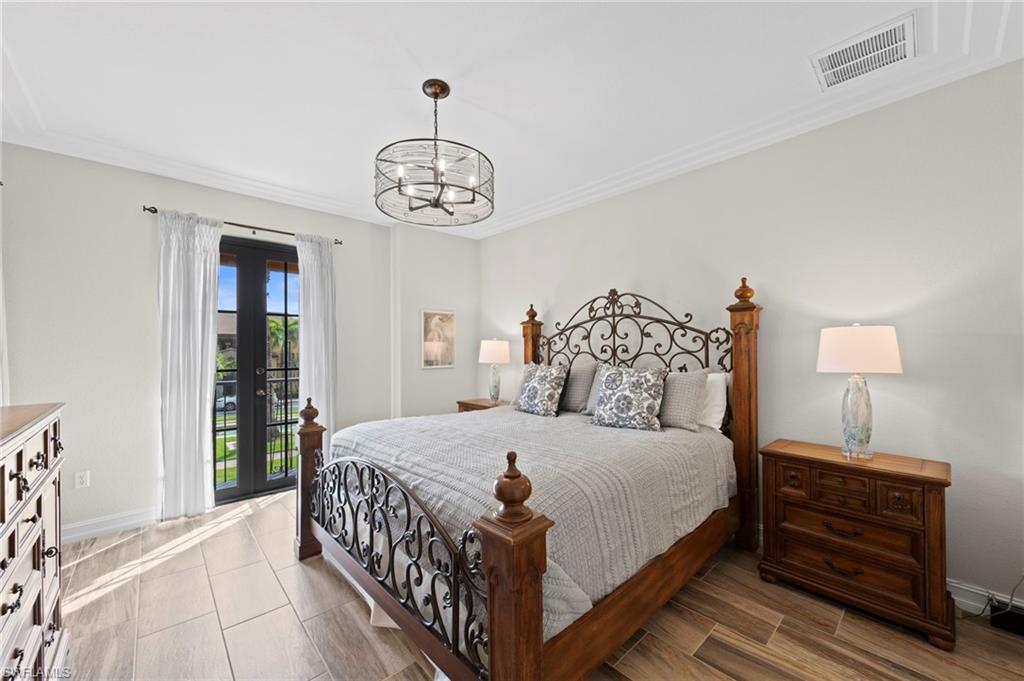 Primary bedroom featuring French doors, wood-finish tile flooring, crown molding, and a drum chandelier. NEW TILE FLOOR (2018)