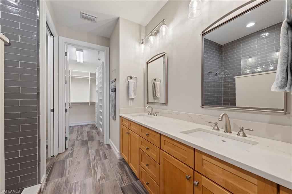 Dual vanity with undermount sinks, light wood cabinetry, and brushed nickel fixtures. NEW QUARTZ COUNTERS (2018), NEW SHOWER REMODEL (2018), NEW MIRRORS (2018), NEW TILE FLOOR (2018)