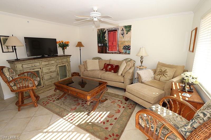 Living area with ornamental molding, light tile patterned flooring, and ceiling fan