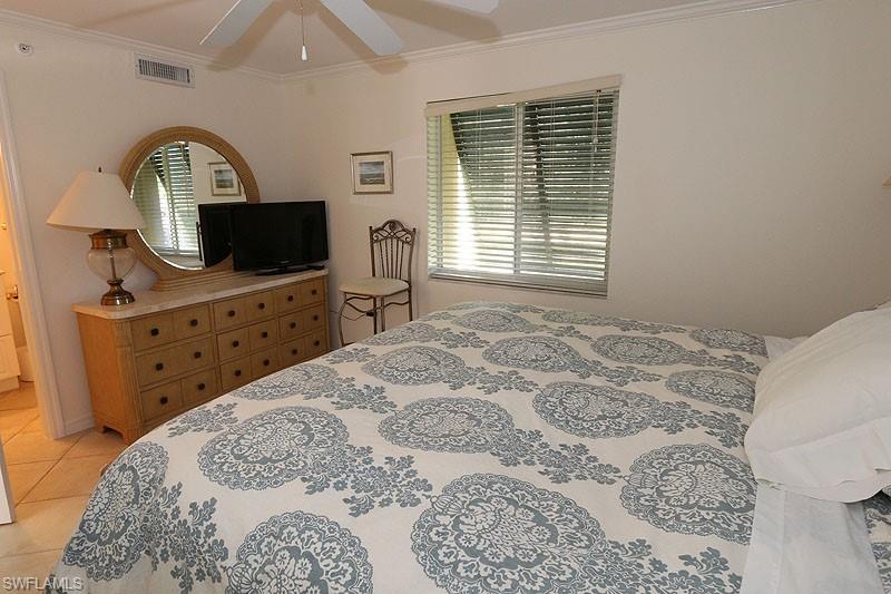 Bedroom with ornamental molding, light tile patterned floors, and ceiling fan