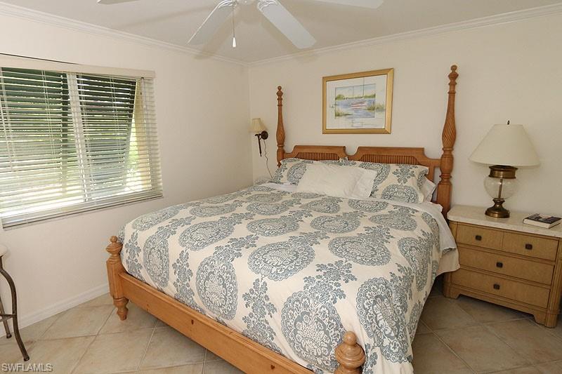 Bedroom with ornamental molding, light tile patterned flooring, and ceiling fan