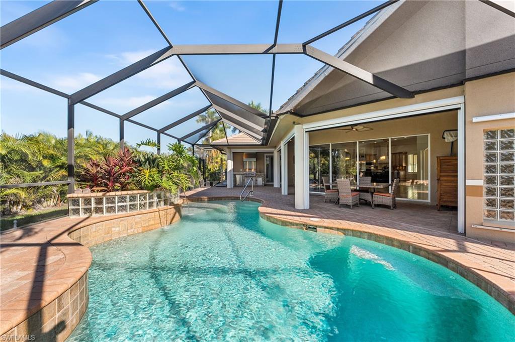 Your outdoor living retreat is thoughtfully curated for elevated coastal entertaining, featuring a premium stainless steel grill with matching hood, integrated refrigerator, and sink—beautifully set within a custom stone-clad built-in station topped with elegant granite. All is sheltered under a spacious covered lanai, further complemented by a private outdoor shower for a true resort-style experience.