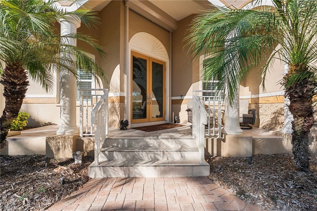 A stunning entryway sets the tone with elegant glass double front doors, creating a grand and welcoming first impression. A beautifully pavered driveway and inviting seating area further enhance the exterior, offering both refined curb appeal and a gracious sense of arrival.