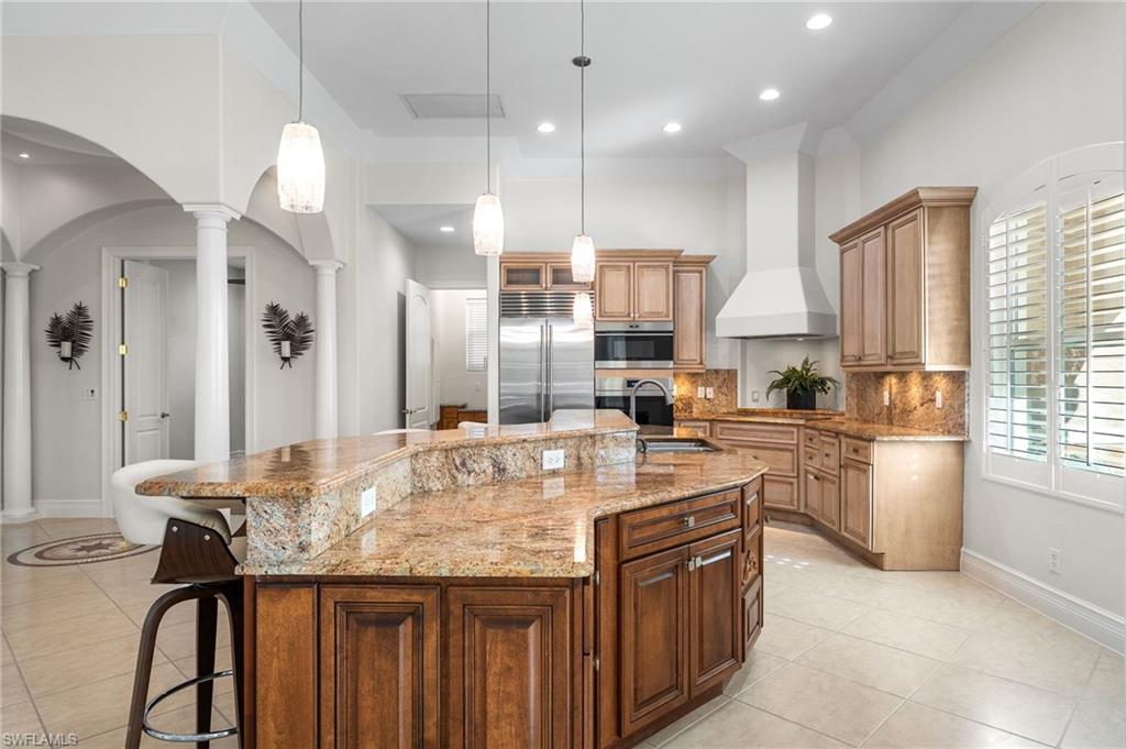 Beautiful custom lighting, complemented by subtle under-cabinet illumination, enhances the refined ambiance of this chef’s kitchen, while a statement high end hood anchors the space beneath soaring ceilings—perfectly showcasing the artistry and grandeur of this architectural masterpiece.