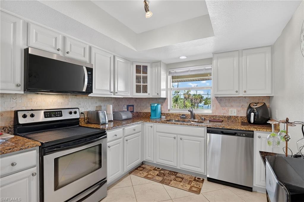 Kitchen featuring white cabinetry, granite-style countertops, stainless steel appliances, and a tiled backsplash