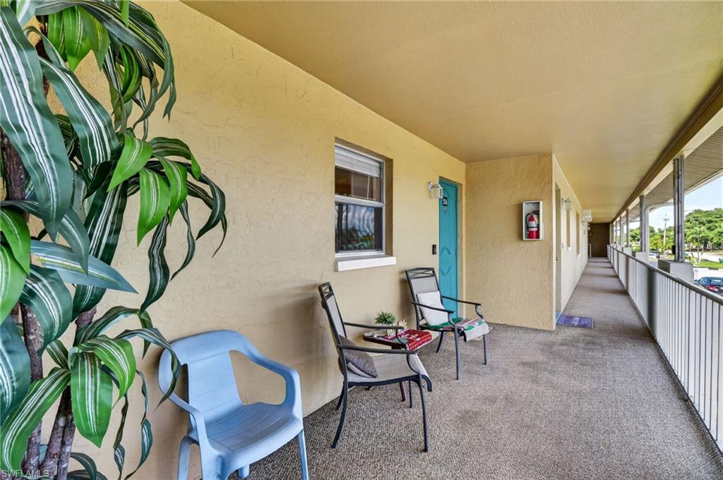 Exterior corridor featuring textured stucco walls, a turquoise entry door, and a textured concrete floor