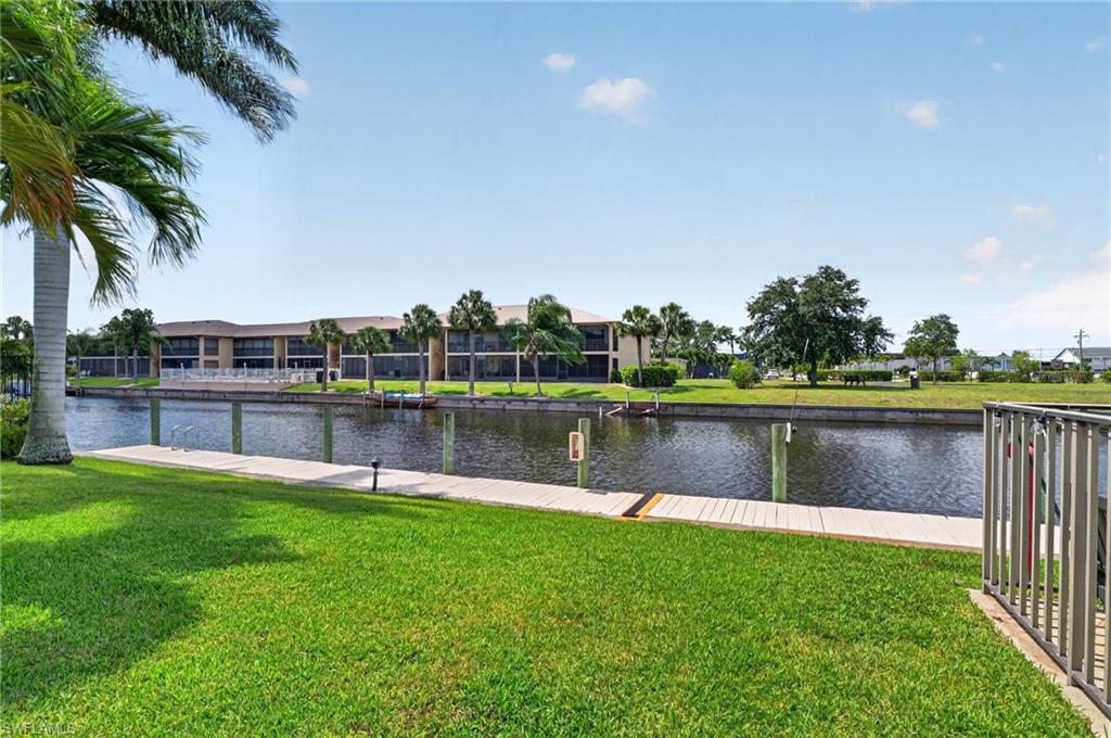 Waterfront property featuring a private boat dock, lush green lawn, mature palm trees, and canal access