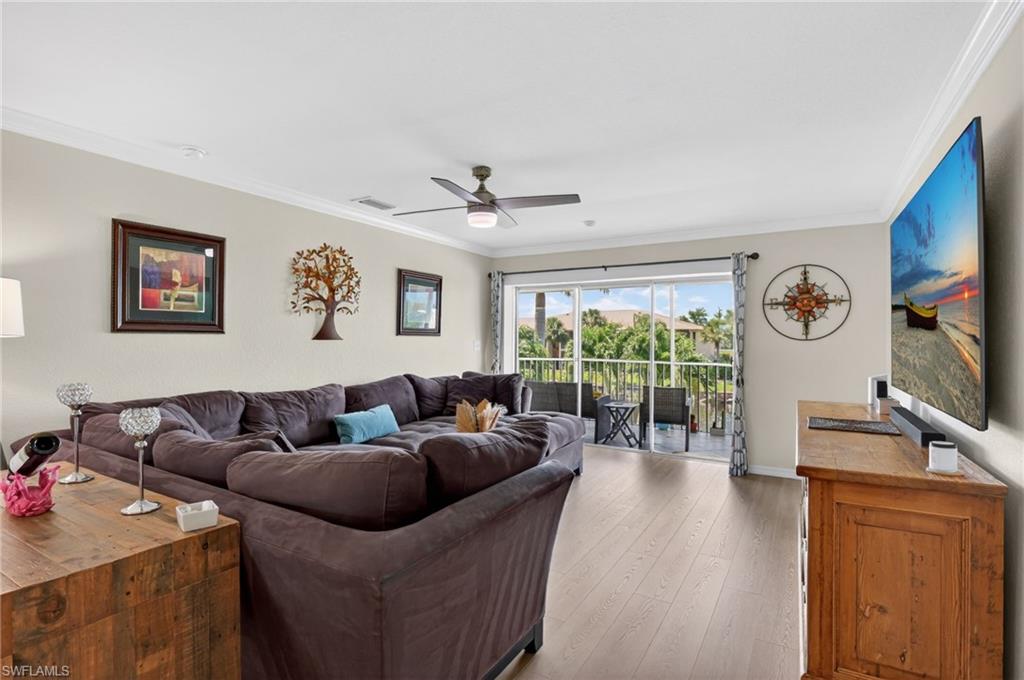 Open-concept living area with wood-finish flooring, crown molding, and a ceiling fan
