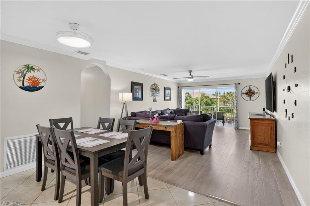 Open concept living area with wood-finish flooring, crown molding, and an arched doorway