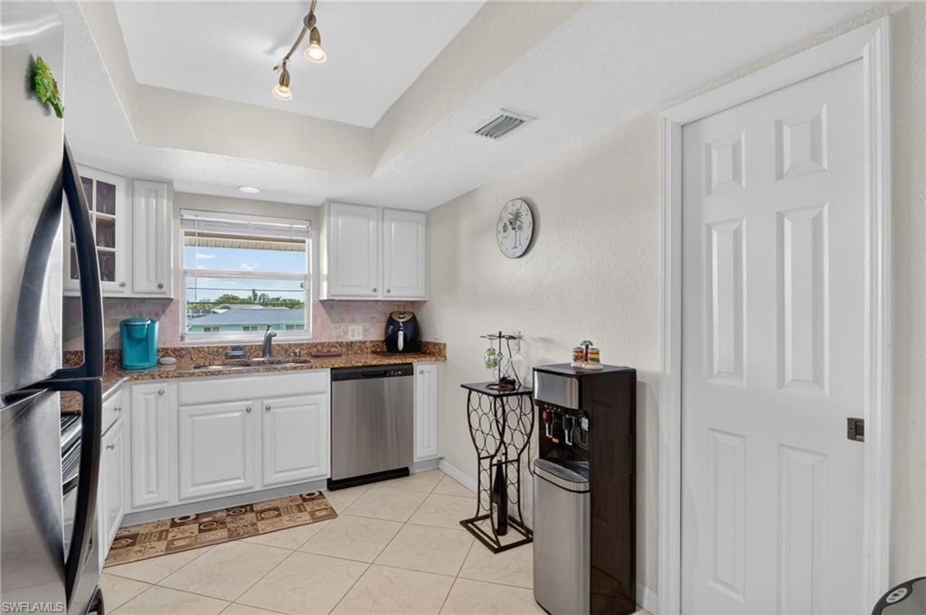 Kitchen featuring white shaker cabinetry, granite-style countertops, stainless steel appliances, and a window with exterior visibility