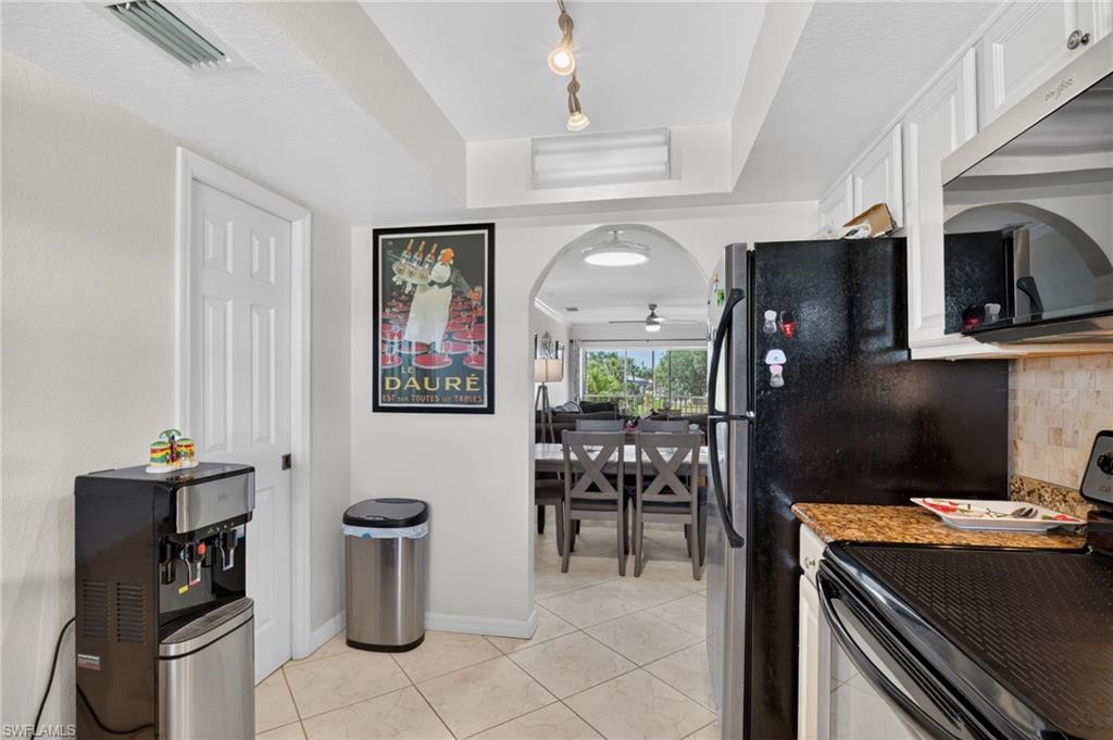 Kitchen featuring white cabinetry, granite-finish countertops, and a tiled backsplash