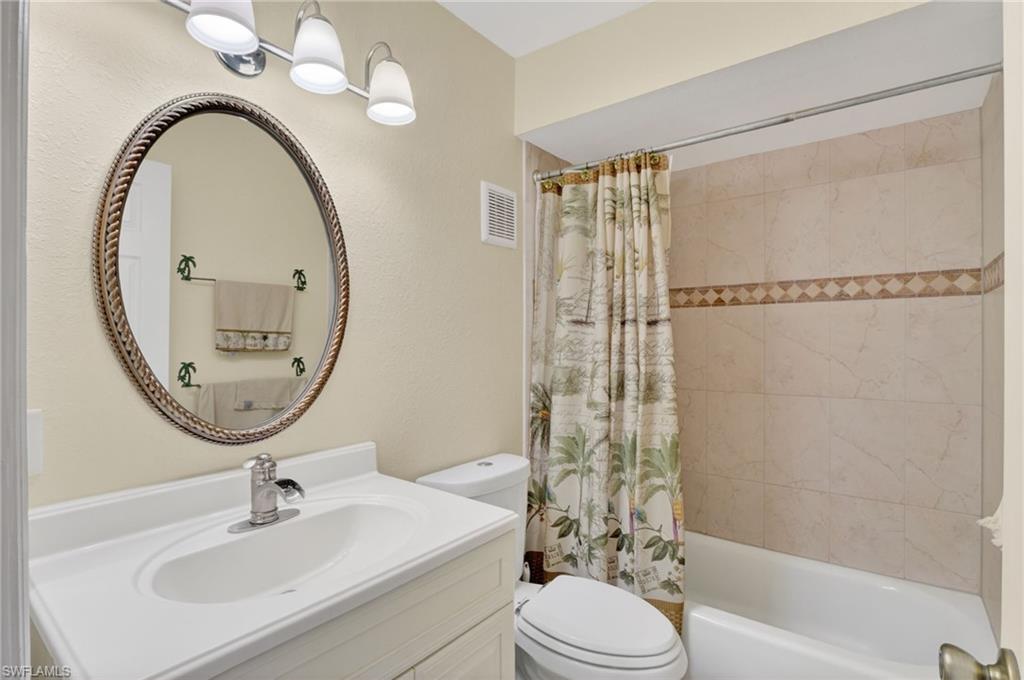 Bathroom featuring a single vanity with an integrated sink, track lighting, and a tiled shower/tub combination