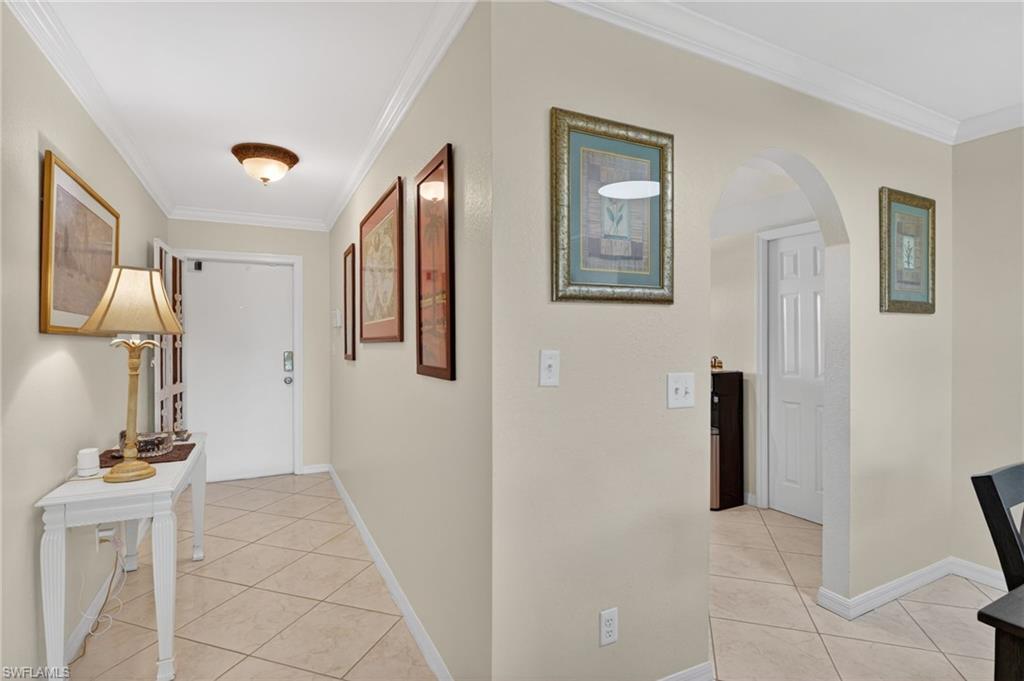 Entryway featuring diagonal tile flooring, crown molding, an arched doorway, and neutral wall tones