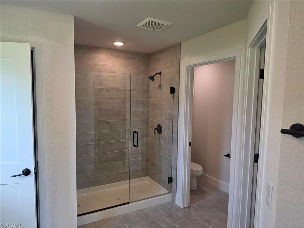 Walk-in shower with clear glass enclosure, tile surround, integrated shower light, and matte black fixtures