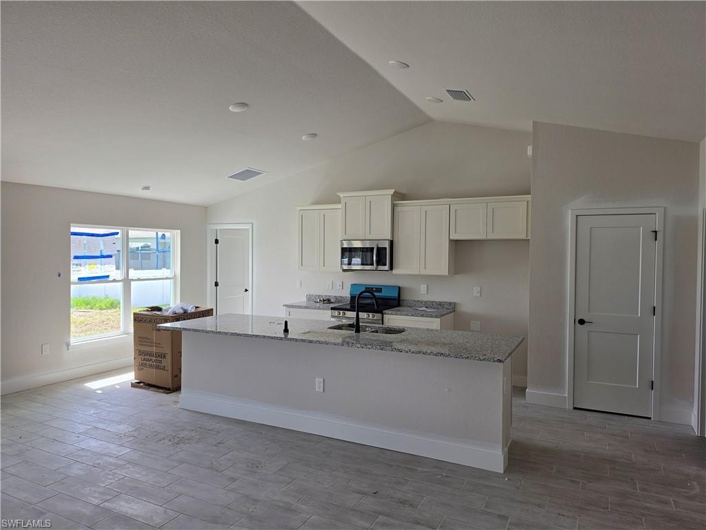 Kitchen featuring an island with a light-toned countertop, cream-colored cabinetry, and stainless steel appliances
