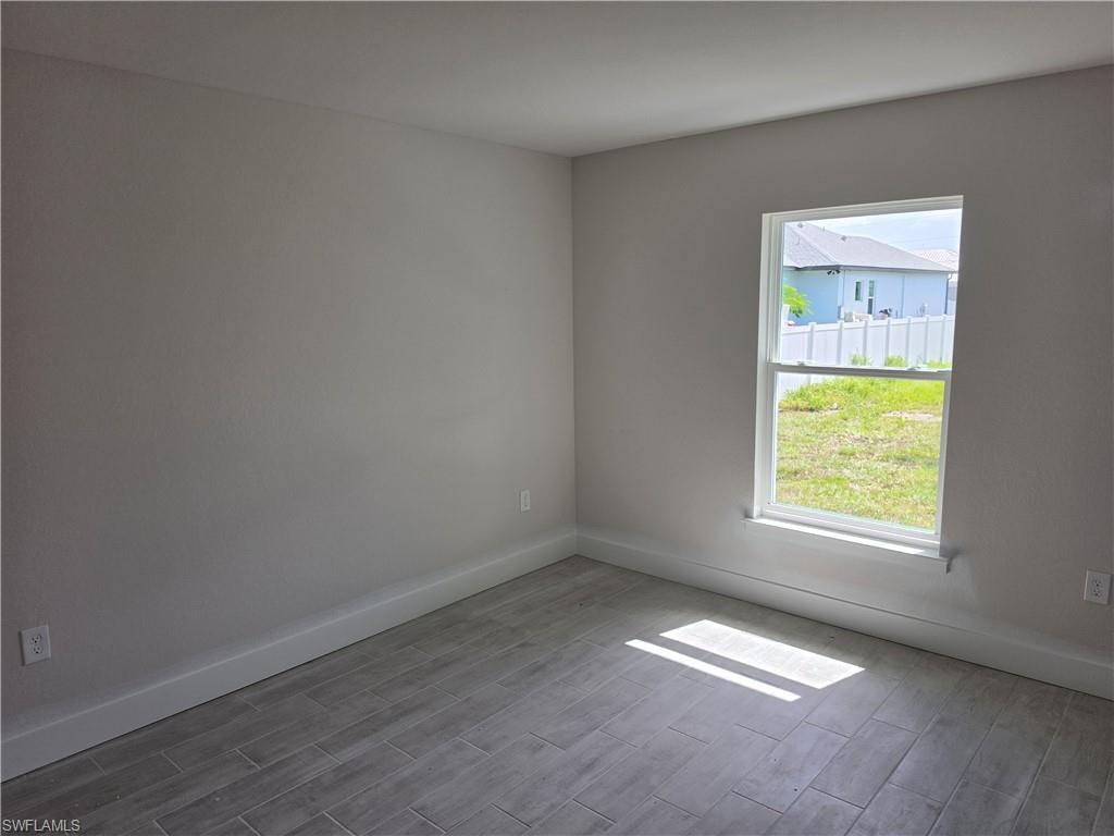 Neutral wall finishes, wood-finish plank flooring, and a single window with white trim