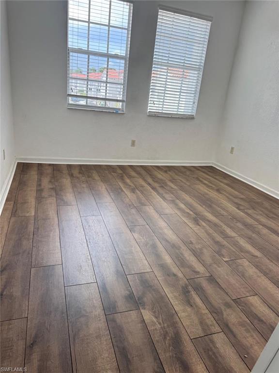 Room featuring wood-finish flooring, white baseboards, and neutral wall tones