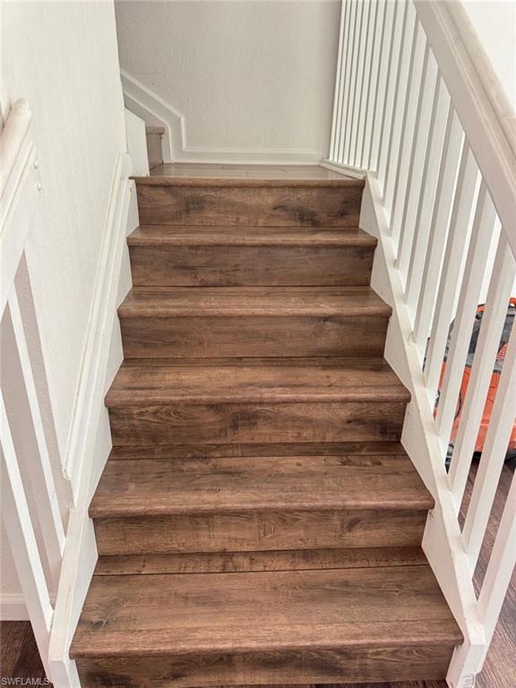 Staircase featuring wood-finish treads, white risers, and white balusters with a matching handrail
