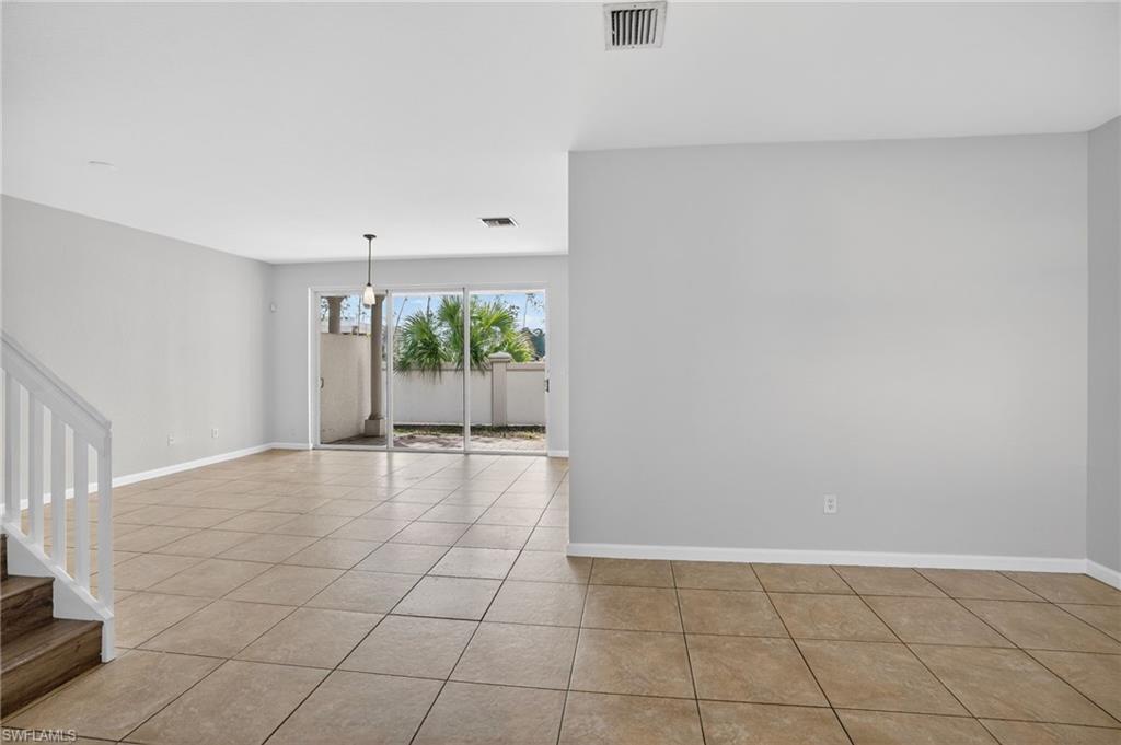 Open-concept living space with square tile flooring, light neutral wall paint, and white trim
