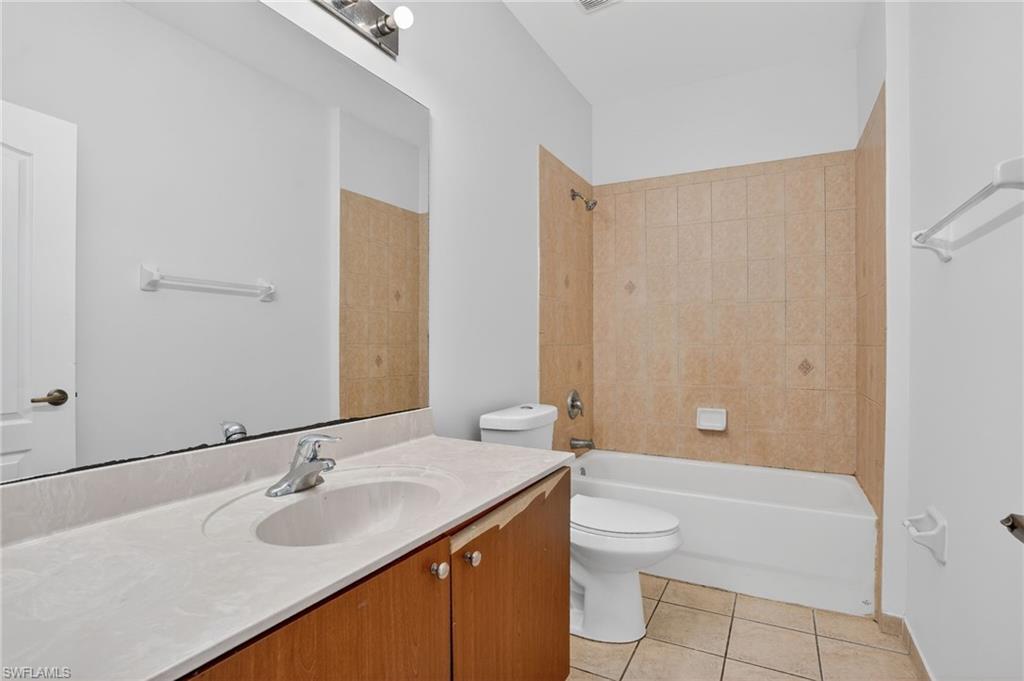 Bathroom featuring a single vanity with integrated sink, wood-finish cabinetry, and a large wall-mounted mirror