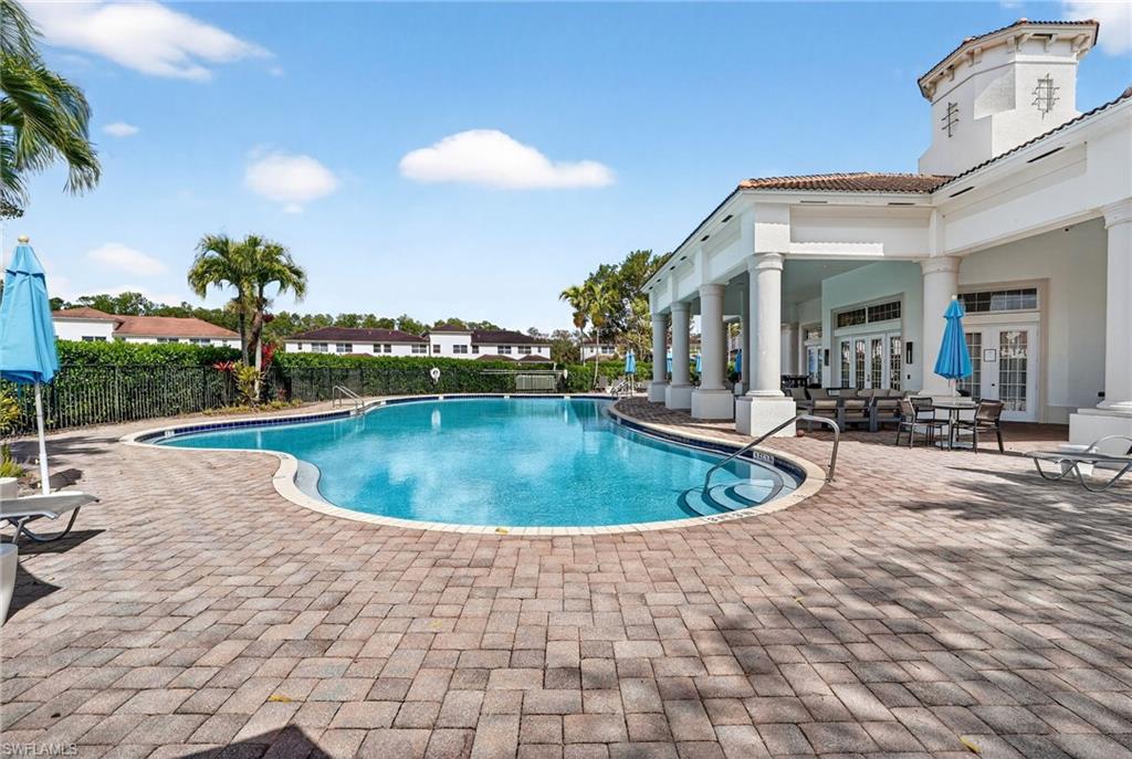 Resort-style swimming pool featuring paver decking, curved entry steps, and a decorative perimeter fence