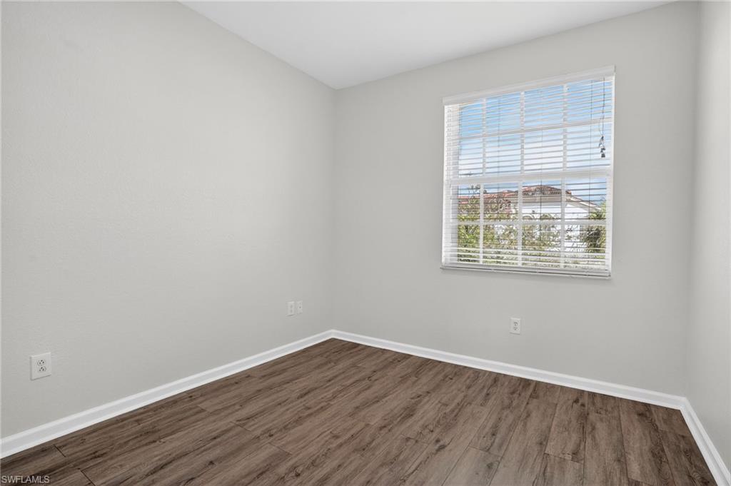 Room featuring light gray walls, wood-finish flooring, and a window with horizontal blinds