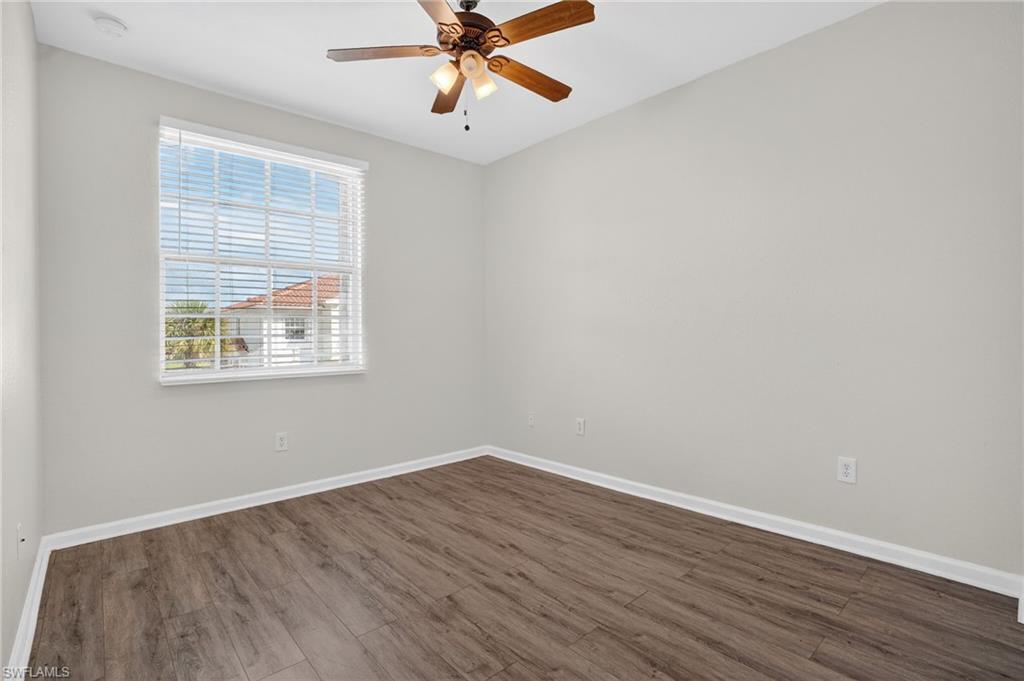 Room with wood-finish flooring, white baseboards, and neutral wall paint