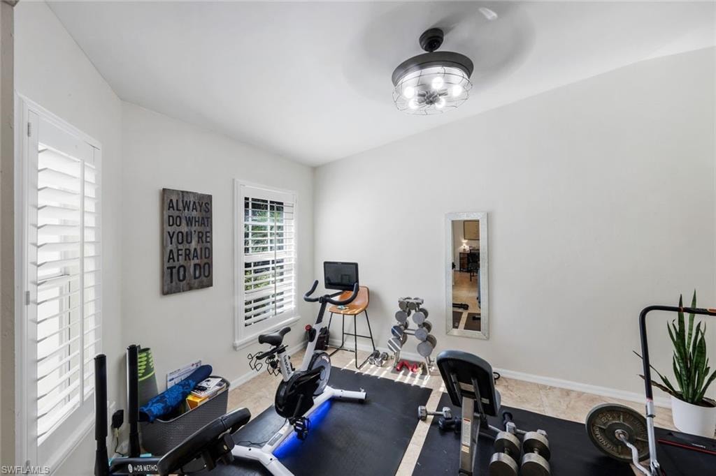 Versatile room featuring two windows with white plantation shutters, a modern ceiling light fixture, and neutral wall tones