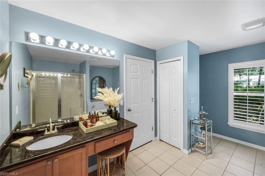 Bathroom featuring a wood-finish vanity with a dark countertop and integrated sink, a large wall mirror, and a multi-bulb vanity light fixture