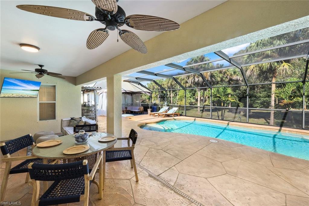 Screened-in lanai with a swimming pool, textured concrete decking, and a covered patio