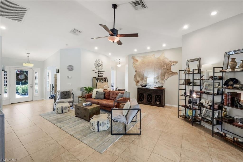 Spacious interior featuring a vaulted ceiling with recessed lighting, large format tile flooring, a prominent ceiling fan, and a double-door entry with sidelights