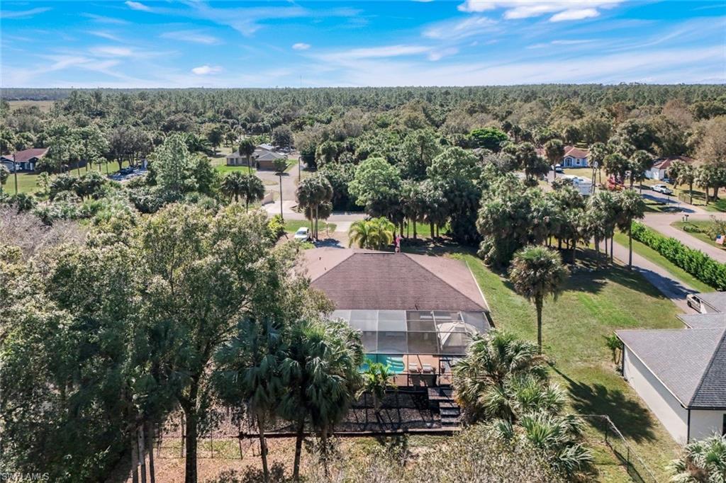 Aerial perspective showcasing a single-story residence with a screened-in pool enclosure