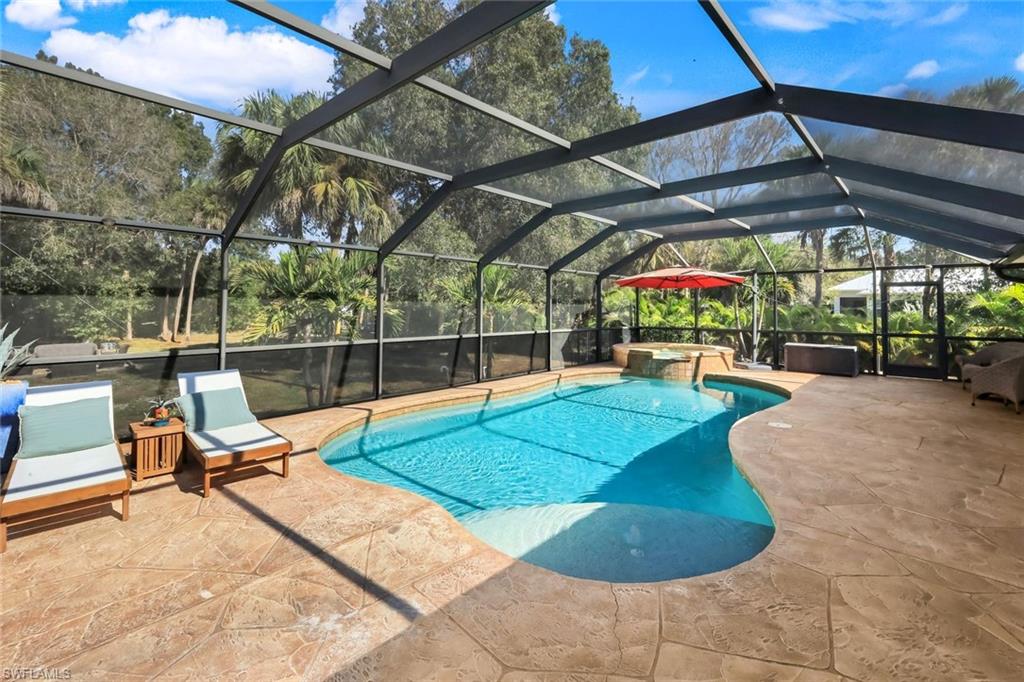 Lanai featuring a freeform swimming pool, integrated spa with waterfall feature, and ample stamped concrete decking