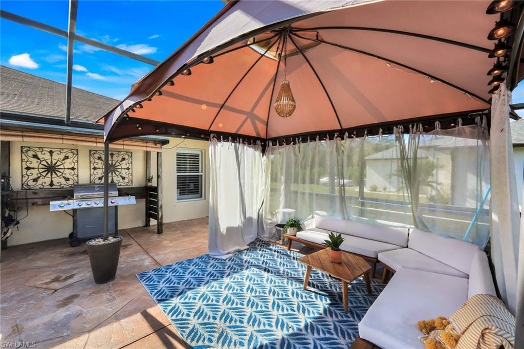 Covered patio space featuring a screened enclosure, stamped concrete flooring, and a built-in outdoor kitchen area