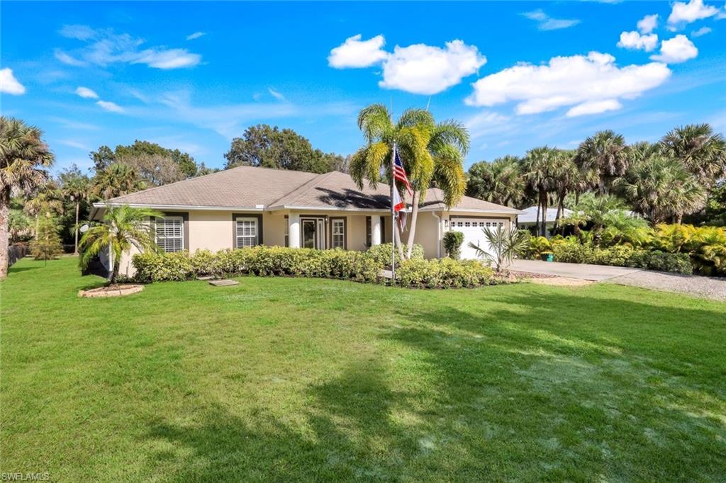 Single-story residence featuring a light-toned exterior, an attached two-car garage, and a lush green lawn