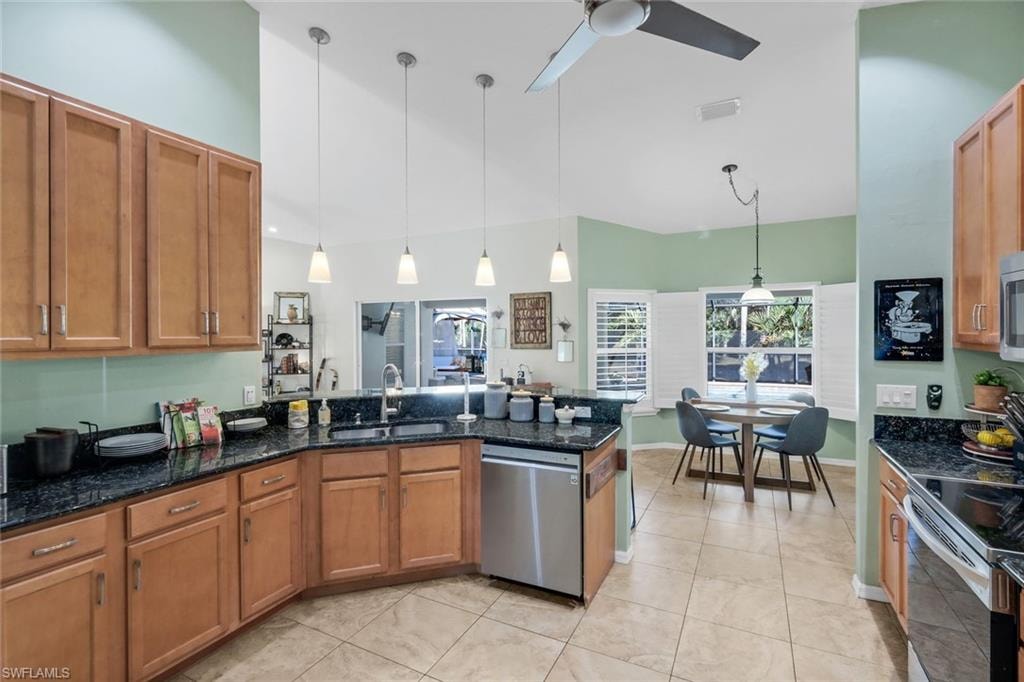 Kitchen featuring wood cabinetry, dark granite countertops, stainless steel appliances, and a tile backsplash