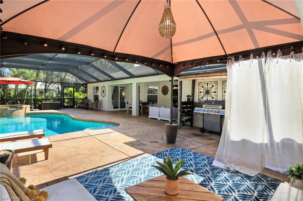 Expansive screened-in lanai featuring a freeform swimming pool, integrated spa, and textured concrete decking