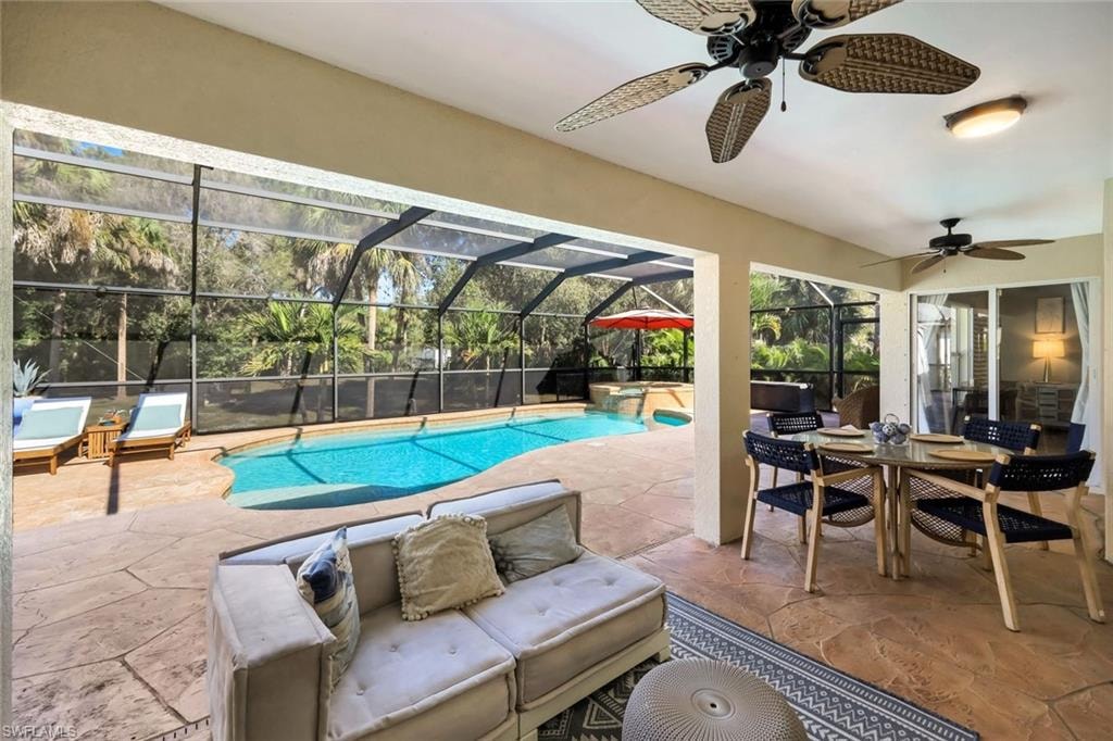 Screened-in lanai featuring a freeform swimming pool, integrated spa, and textured concrete decking