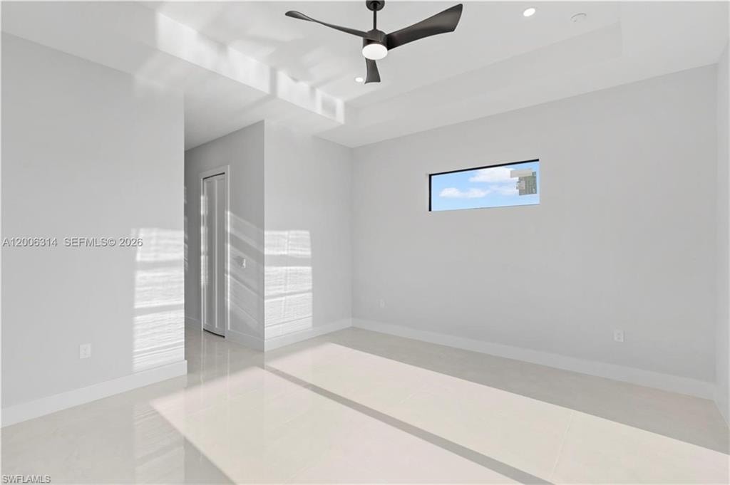 Spacious room featuring light-colored tile flooring, a modern black ceiling fan, and recessed lighting