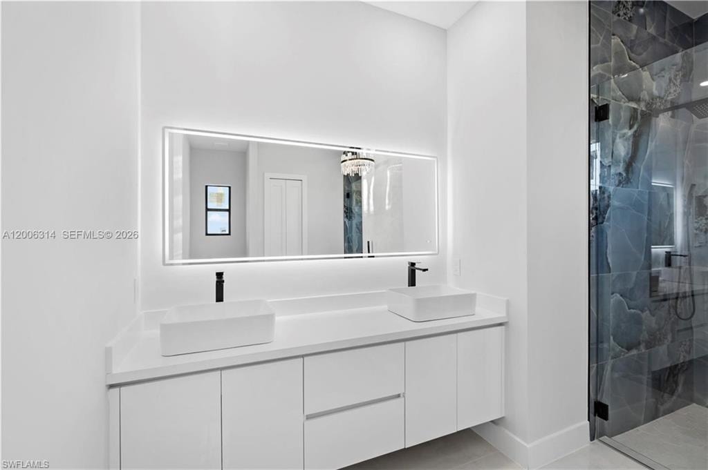 Contemporary bathroom featuring a double vanity with vessel sinks, an illuminated mirror, and a frameless glass shower enclosure with large format tiling