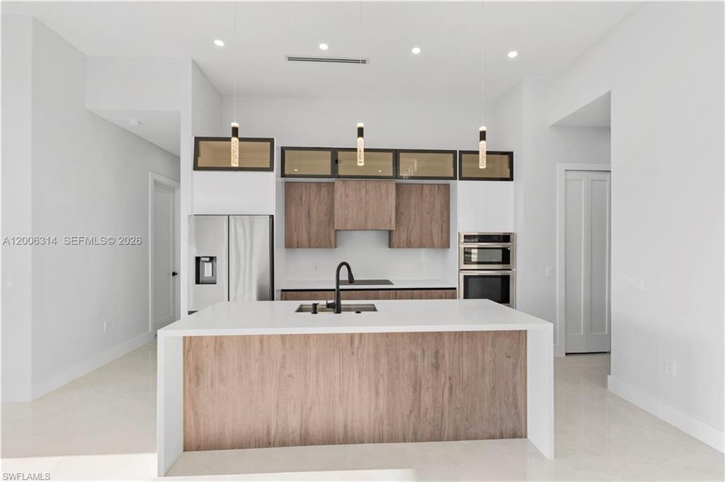 Modern kitchen featuring a waterfall island with a light wood-finish panel, white countertops, and a black matte faucet