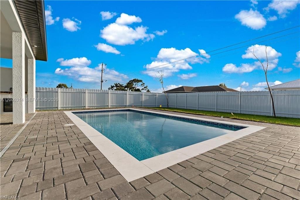 Rectangular swimming pool with a mosaic tile interior, framed by a light-colored coping