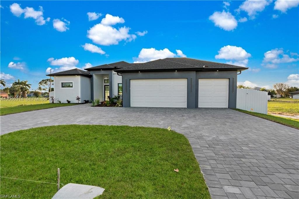 Contemporary exterior featuring a paver driveway, two-car garage, white siding, dark gray stucco accents, and a dark shingle roof